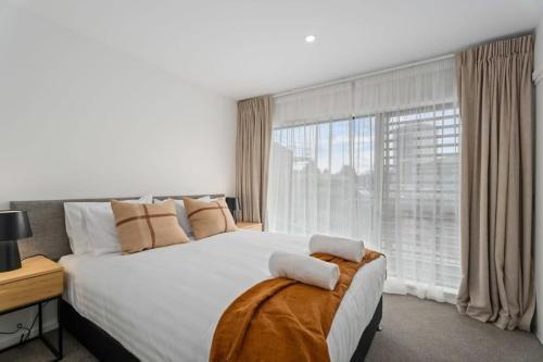 a bedroom with a large bed and a large window at Alps and Lake Retreat Wanaka in Albert Town