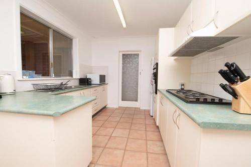 a kitchen with white cabinets and green counter tops at Cadogan House - Professionally Styled in CBD in Orange