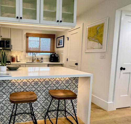 a kitchen with two bar stools at a counter at Surf Casita - Luxury Beach Home - Steps to Ocean & Walk to everything in Newport Beach