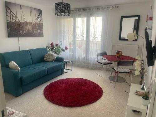 - un salon avec un canapé bleu et un tapis rouge dans l'établissement Beau F1 lumineux et calme, à Chilly-Mazarin