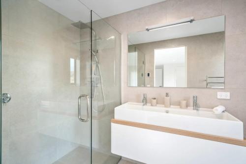 a bathroom with a sink and a shower with a mirror at Chateau Shotover in Queenstown