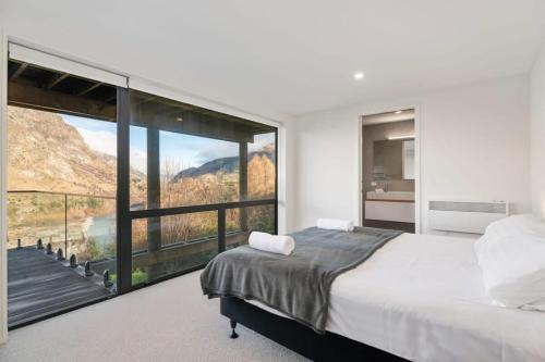 a bedroom with a large bed and a large window at Chateau Shotover in Queenstown