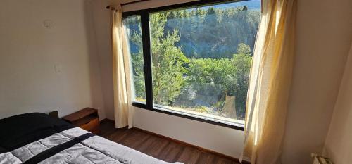 a bedroom with a large window with a view at Casa del Rio in Lago Meliquina