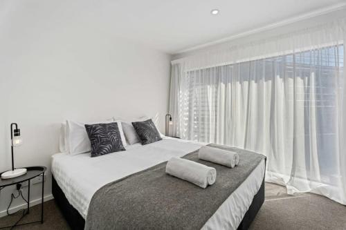 a white bedroom with a large bed and a large window at Alpine Adventurer's Abode in Albert Town