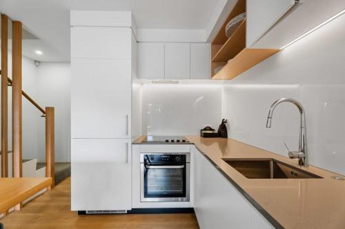 a white kitchen with a sink and a stove at Adventure Riverside Retreat in Albert Town