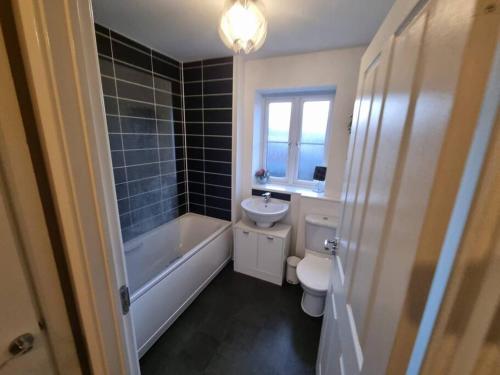 a bathroom with a tub and a toilet and a sink at New Built Immaculate Condition in Rainham