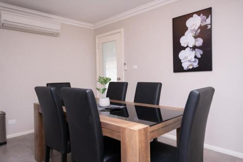 a dining room with a wooden table and black chairs at Wonderful Windred - Quiet & Homely, 4 Smart TVs in Orange