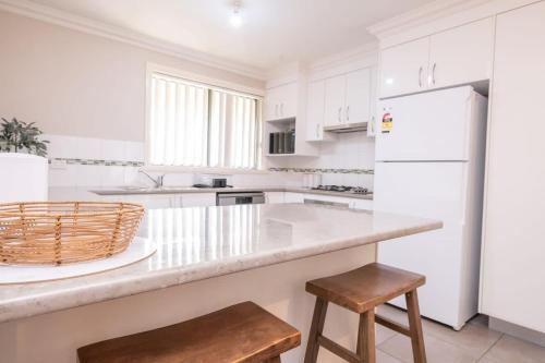 a white kitchen with a counter and a white refrigerator at Wonderful Windred - Quiet & Homely, 4 Smart TVs in Orange
