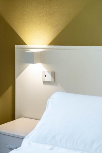 a bedroom with a white bed with a light above it at Le camere sui colli in La Spezia