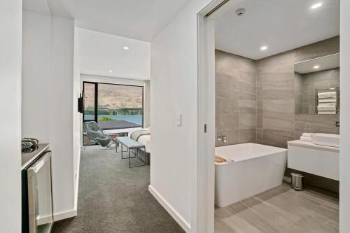 Baño blanco con bañera y lavamanos en Lakefront Premier Studio, en Wanaka