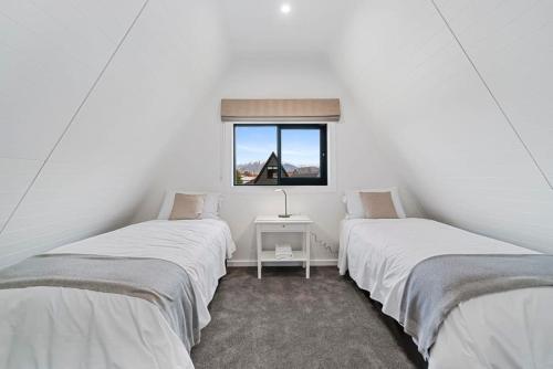two twin beds in a room with a window at MJ's Cottage Arrowtown in Arrowtown