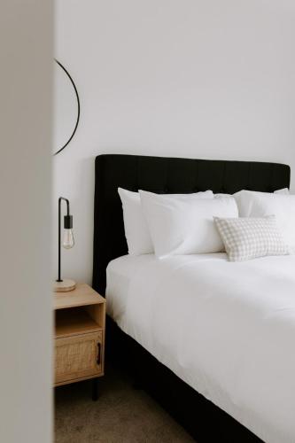 a bed with white pillows and a lamp on a night stand at Dovecote: 5-bedroom Home with Hot tub & Games room in Arrowtown