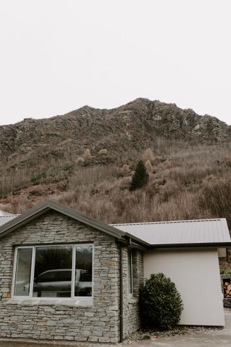 a brick house with a mountain in the background at Dovecote: 5-bedroom Home with Hot tub & Games room in Arrowtown