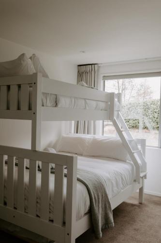 a white bunk bed in a bedroom with a window at Dovecote: 5-bedroom Home with Hot tub & Games room in Arrowtown
