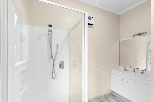 a white bathroom with a shower and a sink at Paradise in Pohara in Pohara