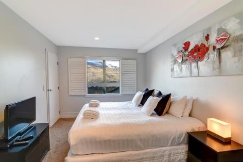 a bedroom with a large bed and a flat screen tv at Modern 3 bedroom with stunning postcard views! in Queenstown