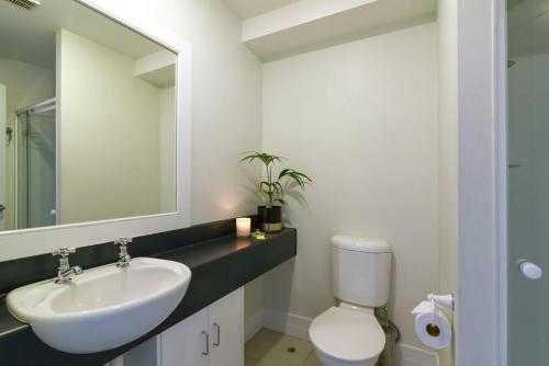 a bathroom with a sink and a toilet and a mirror at Modern 3 bedroom with stunning postcard views! in Queenstown