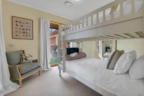 1 dormitorio con litera y silla en Snowline - Ultimate Getaway, Pool & Spa, Sleeps 16, en Canobolas