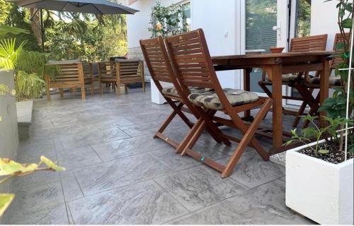 a patio with a wooden table and rocking chairs at Apartments Artemus Karliva in Izola