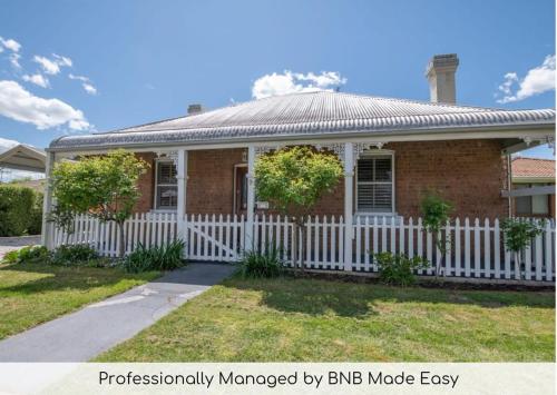 a brick house with a white fence at Secret Cottage - Charming & Lovingly Restored, Firepit in Orange