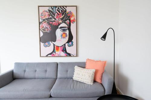 a living room with a gray couch and a painting at Haven on Hill - Modern & Charming, Touch of Pink in Orange