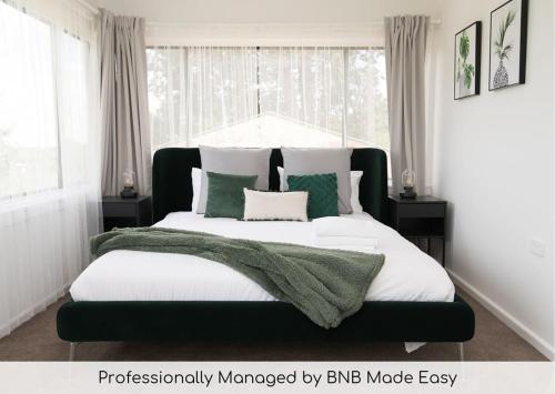 a bedroom with a large bed with green and white pillows at Canobolas Cottage - Amazing Farm Stay, 4 King Beds in Canobolas