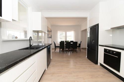 a kitchen with black and white counters and a table at Canobolas Cottage - Amazing Farm Stay, 4 King Beds in Canobolas