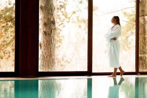 a woman in a robe standing in front of a window at Hotel Borkovac in Ruma