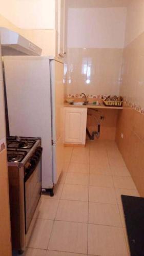 a small kitchen with a stove and a refrigerator at Appartement S+2 richement meublé et climatisé in Potinville