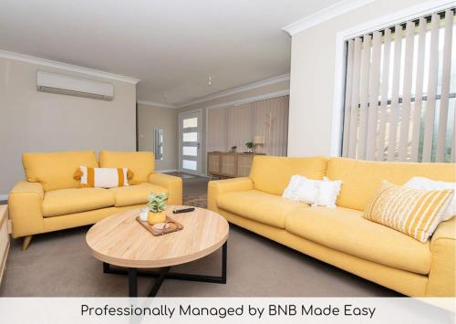 a living room with two yellow couches and a table at Phillip Villa, Modern & Fresh, Close to Town, Free Wifi in Orange