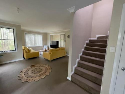 a living room with a staircase and a yellow couch at Phillip Villa, Modern & Fresh, Close to Town, Free Wifi in Orange