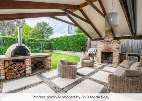 an outdoor patio with a stone fireplace and chairs at Benview Cottage - CBD, Sleeps 8, Pizza Oven in Orange