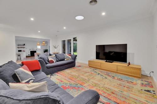 a living room with two couches and a flat screen tv at Benview Cottage - CBD, Sleeps 8, Pizza Oven in Orange