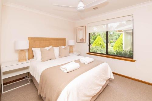 a white bedroom with two beds and a window at Karimi House - Spacious, EV Plug, Sleeps 10 in Orange