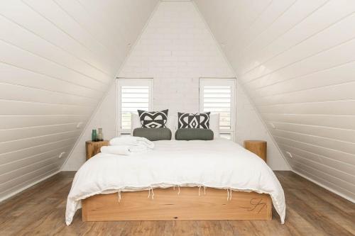 a white bedroom with a bed in a attic at Loft House - On Heifer Station Vineyard in Borenore
