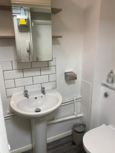 a white bathroom with a sink and a mirror at Clocktower Apartment in Kent