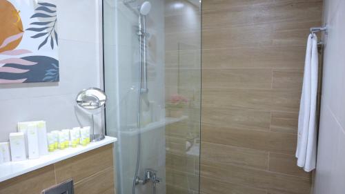 a shower with a glass door in a bathroom at Ivory Haven - Stylish 1BR Apartment in Oasis, Tranquil Stay Near Masdar Park in Abu Dhabi