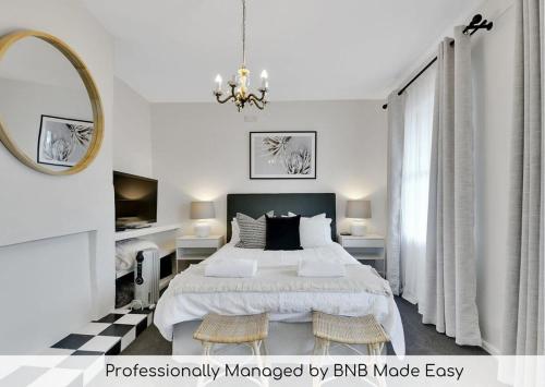 a white bedroom with a bed and a mirror at Clinton Cottage 1860s Heritage Home Walk to CBD in Orange