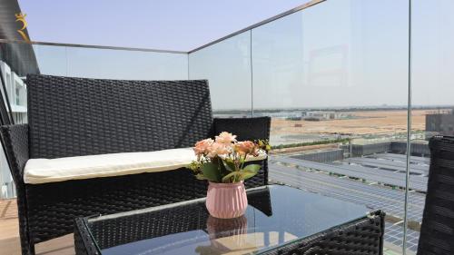 a vase of flowers on a glass table on a balcony at Ivory Haven - Stylish 1BR Apartment in Oasis, Tranquil Stay Near Masdar Park in Abu Dhabi