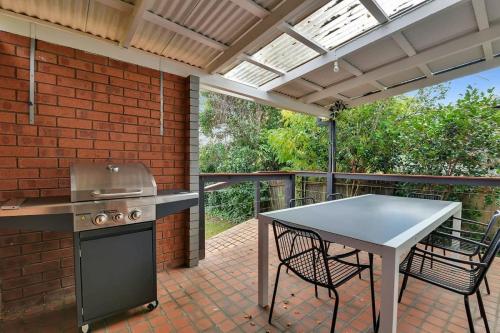 an outdoor kitchen with a table and a grill at Clinton Cottage 1860s Heritage Home Walk to CBD in Orange