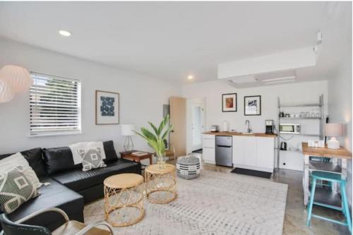 a living room with a black couch and a kitchen at River Breeze Quiet & Modern Black Pearl Apartment in New Orleans