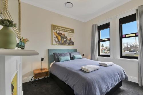 Un dormitorio con una cama y dos ventanas. en Best Nest on March Cosy Home in CBD Firepit, en Orange