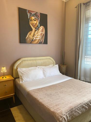 a bedroom with a bed with a painting of a woman at Casa del Court in Kampala