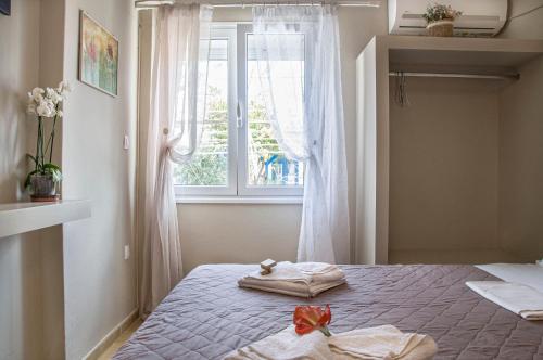 a bedroom with a bed with two towels and a window at Christina Rooms in Adamas
