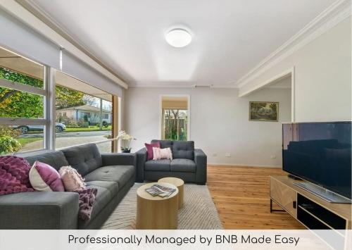 a living room with a couch and a flat screen tv at Collwood Cottage Cosy & Free Wifi in Orange