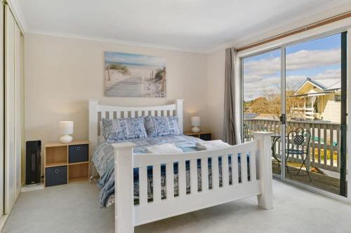 ein Schlafzimmer mit einem weißen Bett und einem großen Fenster in der Unterkunft Collwood Cottage Cosy & Free Wifi in Orange