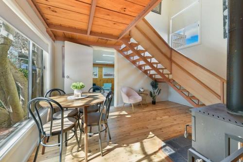 a dining room with a table and chairs and a staircase at Collwood Cottage Cosy & Free Wifi in Orange