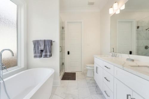 a white bathroom with a tub and a toilet at Stunning Luxury Home 2 Blocks From Streetcar in New Orleans