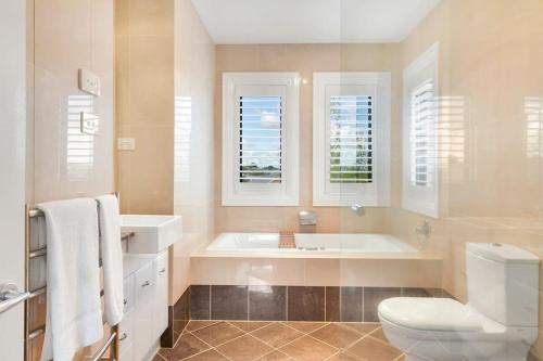 uma casa de banho com uma banheira, um WC e janelas em Roselawn Retreat - Pool, Incredible Views, Sleeps 8 em Orange