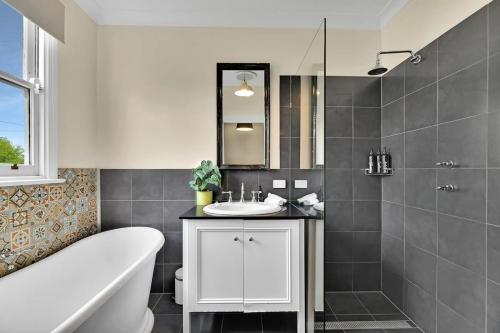 a bathroom with a tub and a sink and a bath tub at Edwina Suite I - Sleek and Stylish CBD Wi-Fi in Orange